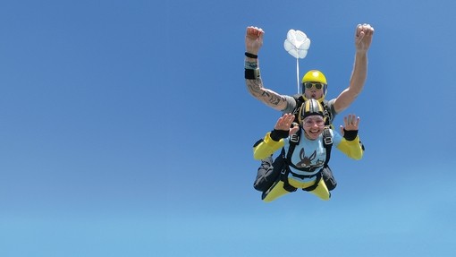 An image of a man and women attached to each other while skydiving.