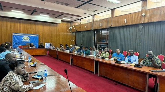 A conference room filled with people sitting at a long U shape desk