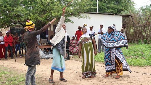 Four actors wearing colourful clothes whilst performing in front of an audience.
