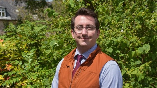 An image of a man wearing glasses, smiling toward the camera.